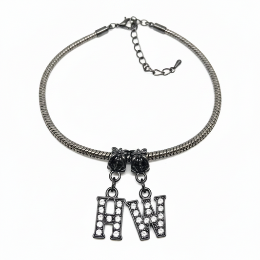 A silver-toned snake chain necklace with two hanging letter charms, one reading 'H' and one reading 'W', both adorned with clear rhinestones, shown on a plain white background.