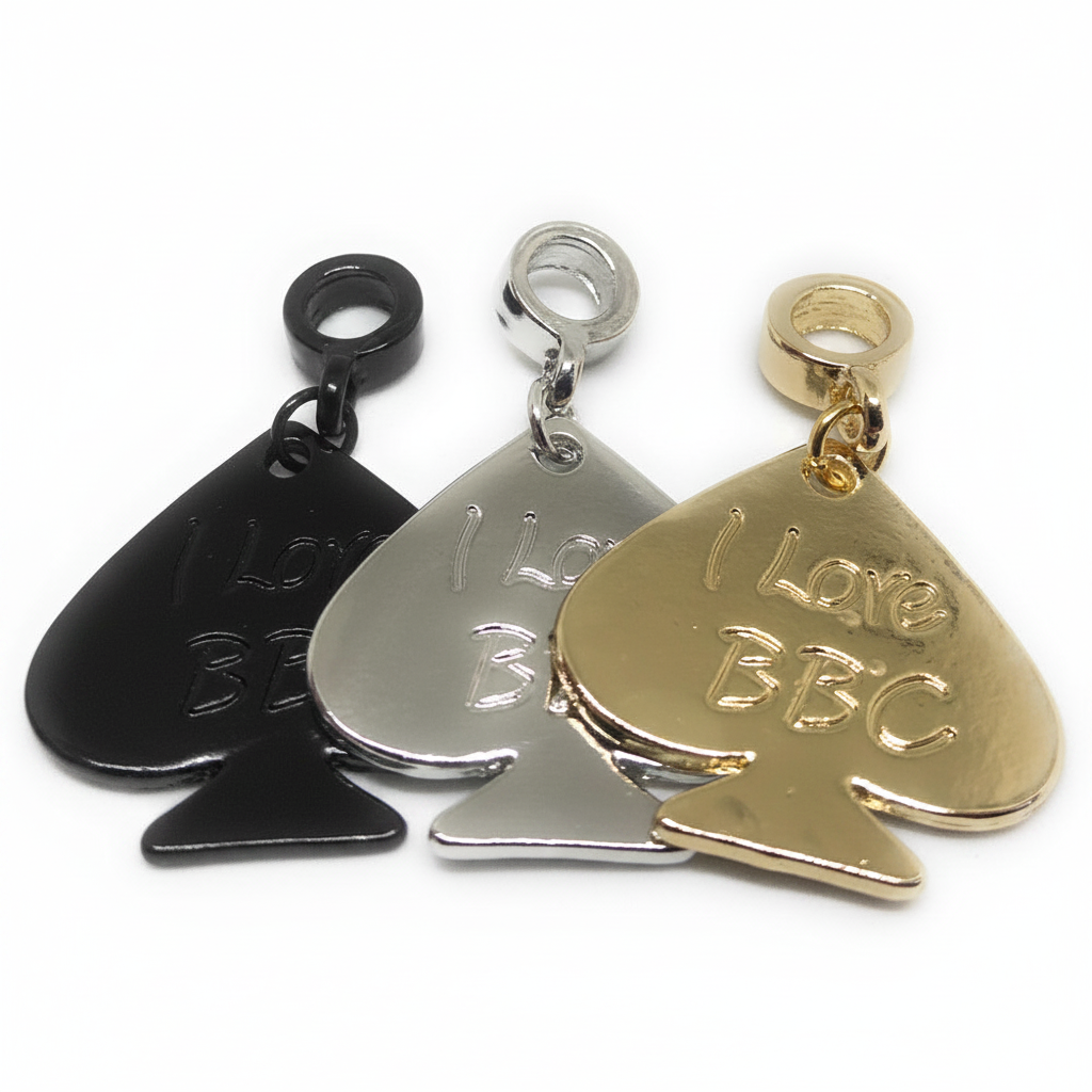 Three pspade-shaped charm pendants on a white background, shown in black, silver, and gold finishes. The pendants feature the engraved text 'I Love BBC' and are displayed overlapping each other.