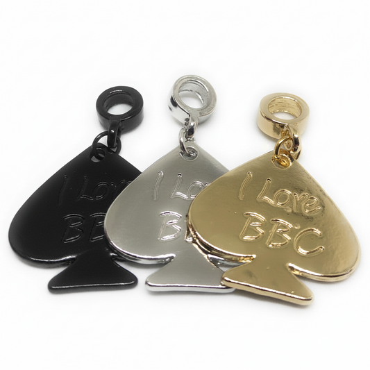 Three pspade-shaped charm pendants on a white background, shown in black, silver, and gold finishes. The pendants feature the engraved text 'I Love BBC' and are displayed overlapping each other.