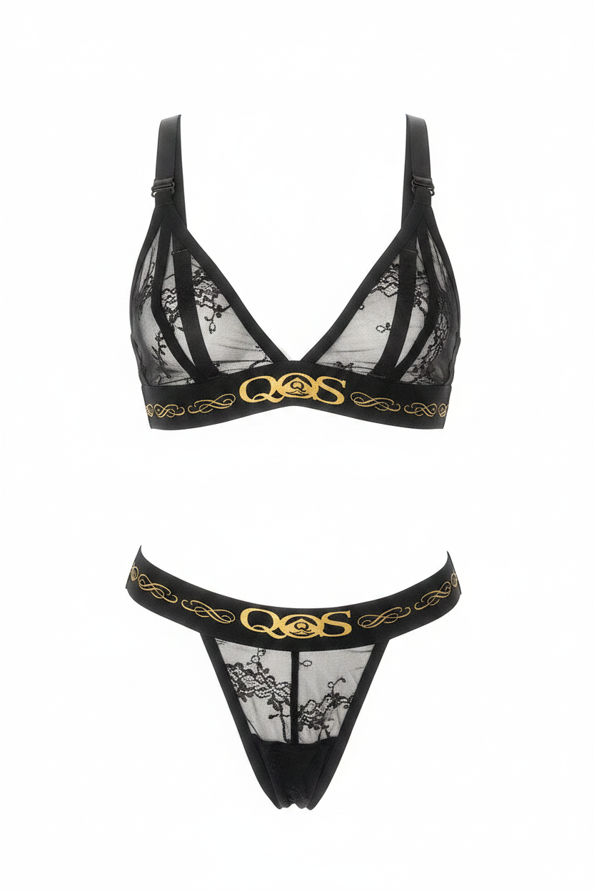 Black lace lingerie set with sheer mesh panels and gold QMS branding on the underband of both bra and thong, shown on a plain white background.