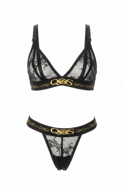 Black lace lingerie set with sheer mesh panels and gold QMS branding on the underband of both bra and thong, shown on a plain white background.