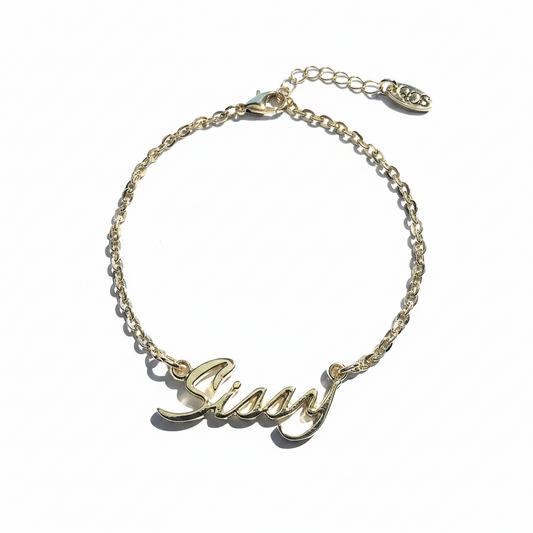 A gold-colored chain anklet with the word 'Sissy' written in a cursive script.