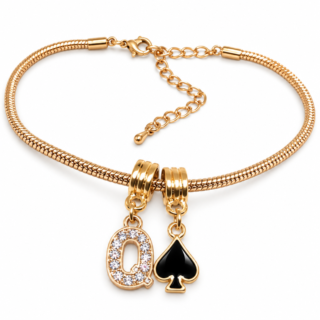 A gold-plated snake chain bracelet featuring two charms: a large letter 'Q' charm encrusted with clear rhinestones and a black spade card charm, displayed on a clean white background.