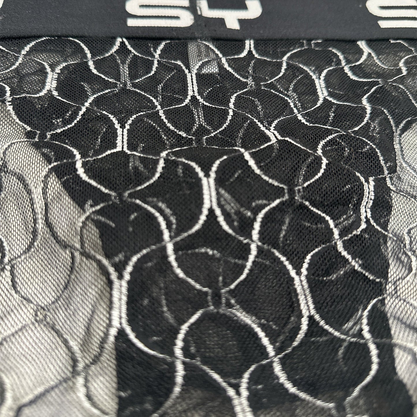 Black lace fabric with a pattern and 'SY' branding on a white background